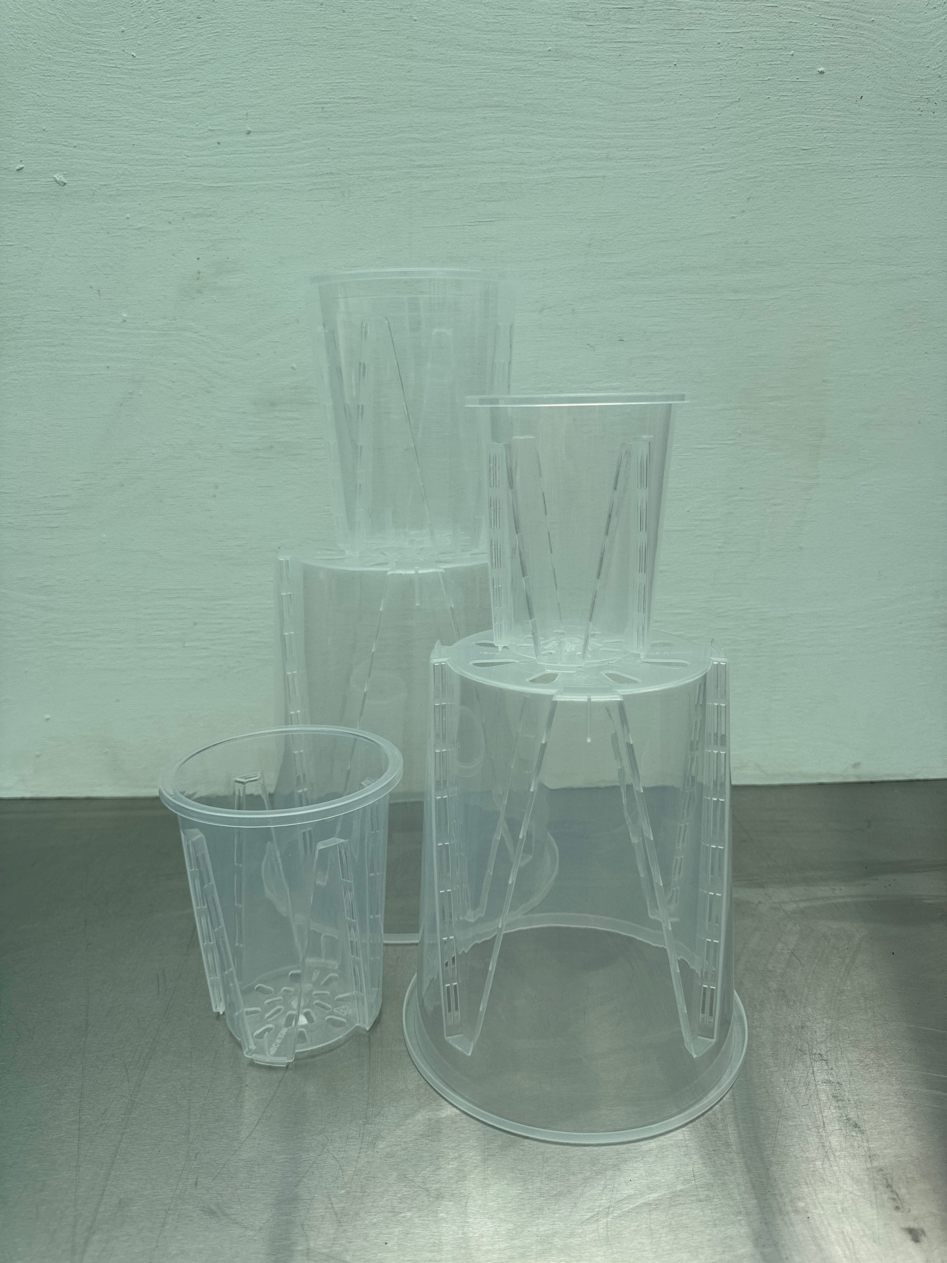 Transparent round planter pot set in various sizes, ideal for tropical and moisture-sensitive houseplants. Clear design aids root monitoring and drainage.