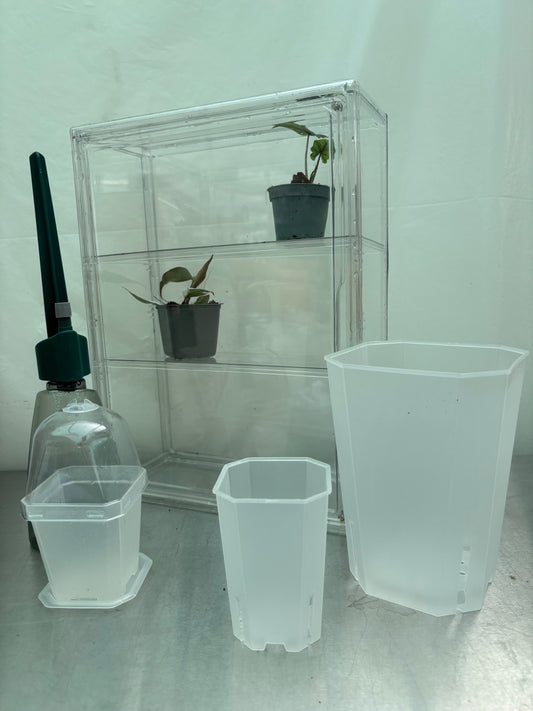 Greenhouse Pro Bundle with clear acrylic greenhouse, potted plants, self-watering tool, and translucent nursery pots for optimal plant growth.