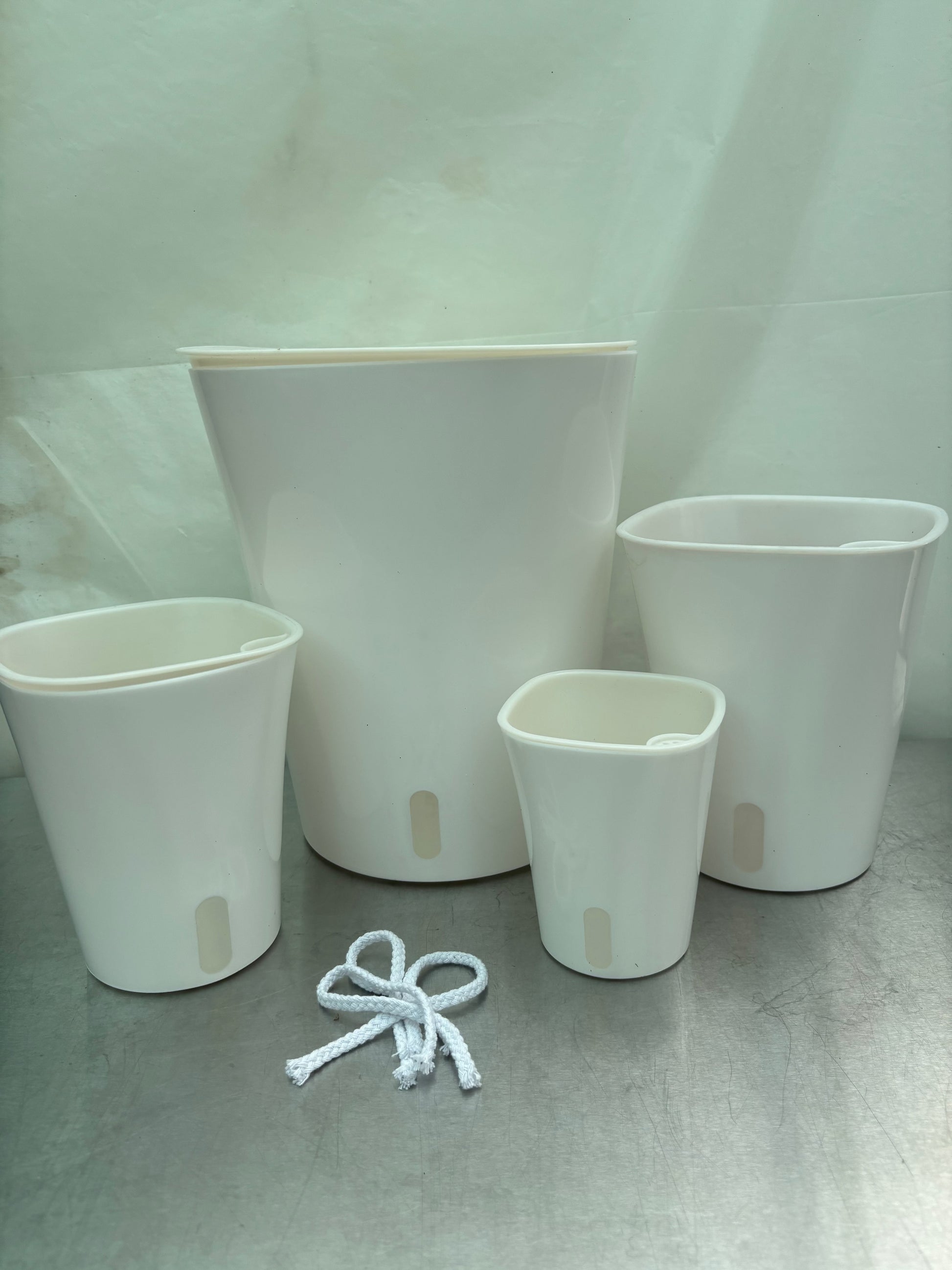 When Should I Water? kit featuring four white self-watering planters in various sizes with water level indicators and included wicks. Ideal for easy plant care.