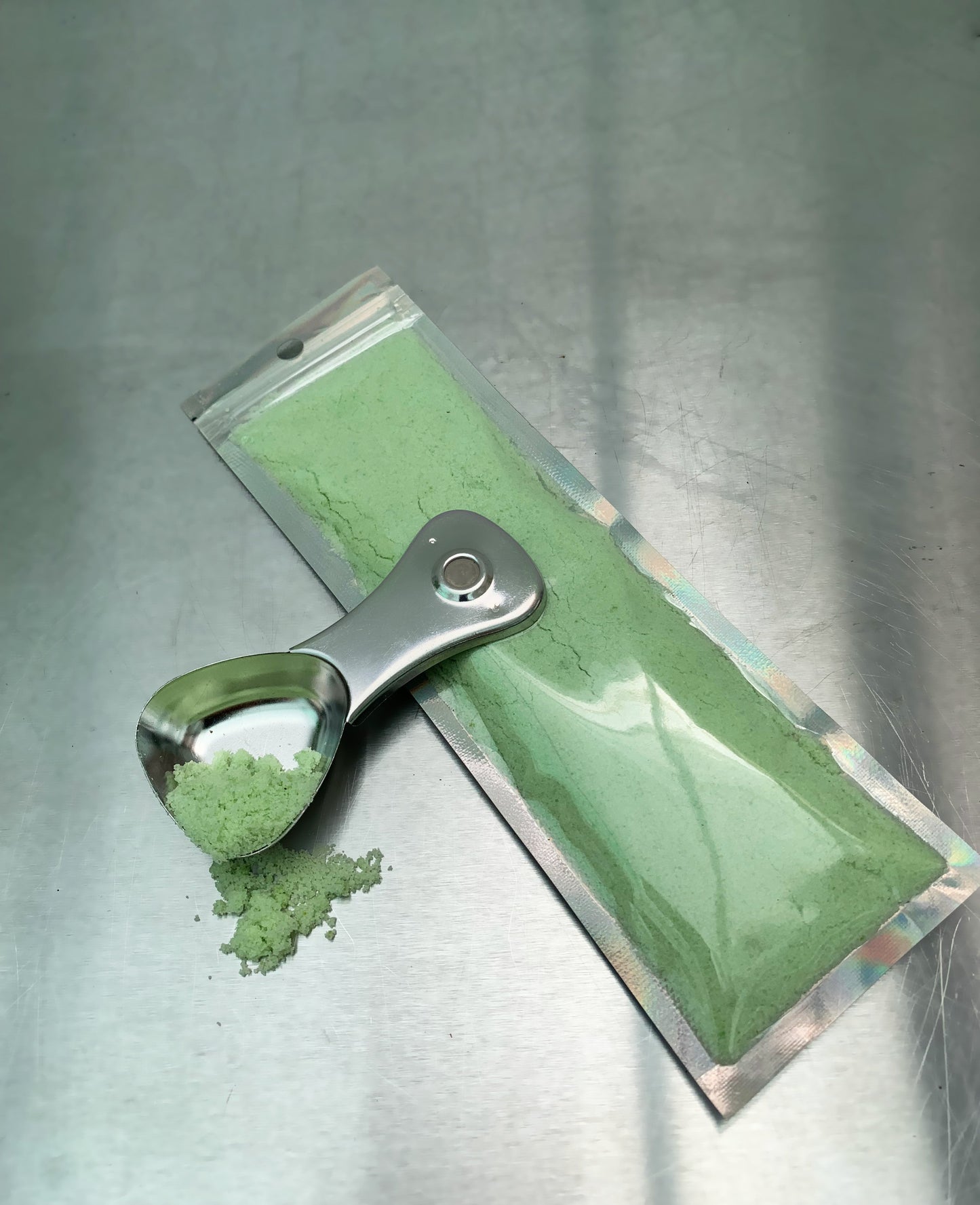 NPK 20-20-20 Fertilizer in green powder form with a metal scoop on a reflective surface. Ideal for balanced plant nutrition in all seasons.